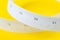 White measuring tapes with centimeter and inches on vivid yellow