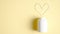 White medical bottle and cardiac medications in heart shape spilling out on to pastel yellow background. Top view with copy space