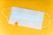 White medical mast with small orange flower on it. intence yellow paper background