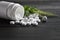 White medical pills and tablets spilling out of a drug bottle. top view with copy space. On Black wood Background. Natural herbs,