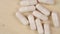 White Medicinal Capsules Close-up. Rotate slowly on a wooden board