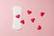 white menstruation pad with red hearts as blood drops on rose background, women critical days concept