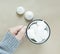 The white merengues in a cup on beige background top view. A cup with merengues marshmallow in women hand