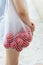 A white mesh string bag with tomatoes is thrown over the shoulder of a girl