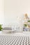 White metal bed frame with gray bedding and a checkered rug in a natural kid bedroom interior with wooden furniture and decoration