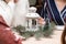 A white metal candlestick with candle inside surrounded with christmas tree. Women sitting around the table. Christmas party or