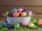 White metal Easter basket filled with sequined Easter eggs on top of a bed of green paper shreds with a real wood background