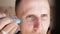 White metrosexual man applying lotion for anti-aging treatment around eye