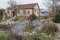 White middle-aged man cleans a garden pond with landing net from slime, water plants, falling leaves and catches fish