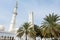 White minaret of the Grand Mosque built with marble stone  and green palm trees, also called Sheikh Zayed Grand Mosque in Abu