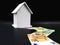 white miniatur house with path of euro banknotes on black background, home finance and banking concept