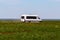 A white minibus stands in the steppe among blooming wild tulips.