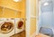 White Modern appliances in small yellow laundry room