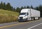 White big rig semi truck transporting dry van semi trailer on th