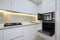 White modern kitchen with a stove, oven and microwave