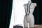 White modern mannequin or dressmakers dummy with gray fabric and hanging measuring tape