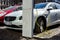 White modern plug-in Volvo car plugged and charging its battery with green electricity