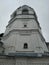 White monastery building. Tall tower. The building is white brick. Grey sky.