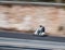 White motorcycle fast along the street on a motion blurred background.