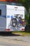 A white motorhome with a cycle carrier attached to the rear with two bicycles and a child`s bike