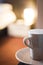 White mug of coffee on saucer in hotel room warm evening light