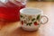 White mug with a pattern on the background of a glass decanter with strawberry compote on the table