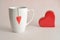 A white mug with a red heart attached to a string