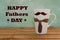 White mug on wooden background with mustaches. Father`s Day funny greeting card