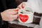 white mugs in the form of hearts in the hands of the bride and groom. Valentine`s day, the day of Love and marriage