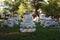 White murble buddha sculpture meditating, with asian lions in a garden with green grass at sunset time.