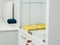 White new cabinet with yellow folder behind closed glass doors. Inserted red key into the lock on drawer. Minimalistic light cupbo