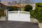 White new metal driveway entrance home gates in modern suburb house