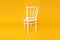 White nice wooden chair on a yellow background in the studio