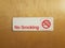 white no smoking sign on brown door with cigarette