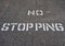 White No Stopping Sign Stenciled on Black Road