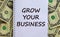 White note with inscription `grow your business` on beautiful background from dollar bills. Concept