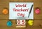 White note with inscription `World Teachers` Day` on beautiful wooden table, colored paper, metalic pen and wooden calender wit