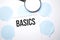 White noteapad and magnifier on blue speech bubles. Text BASICS. Business concept