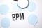 White noteapad and magnifier on blue speech bubles. Text bpm. Business concept