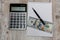 White notebook, dollars, calculator and pen on a wooden table