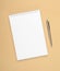White notebook with steel pen on a brown background. Office, save space, mock up, template, top view, flat lay.