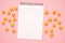 White notebook and sweet yellow candies on a pink background