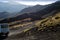 White off-road car bypasses extinct craters of the Etna volcano with black lava around