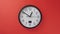 White office clock hanging on a red color wall