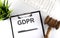 White office desk table with blank sheet , text GDPR , keyboard and gavel, top view