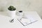 White office desk table mock-up scene with cup of coffee, cactus, open notebook, blank greeting card, envelope and