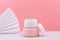 White opened cosmetic jar on pink gypsum podium against pink background with waver and copy space
