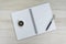 White opening blank paper note book with pen on the right and navigation compass on light grey wooden table background with copy