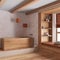 White and orange farmhouse bathroom with wooden bathtub. Window with bench and pillows, plaster concrete walls. Japandi interior