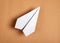 White origami plane on brown background. Paper folding art. Architecture model.